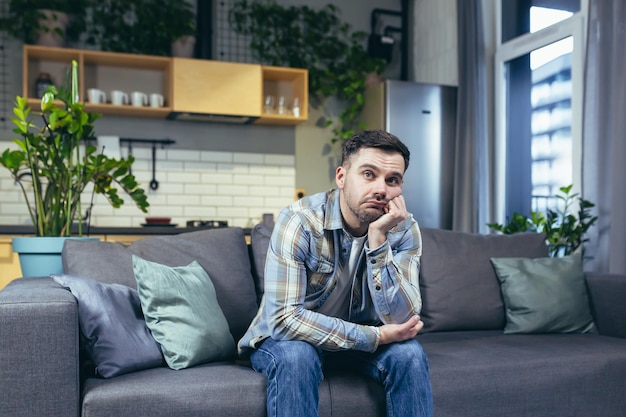 Sad and pensive man sitting on the couch at home