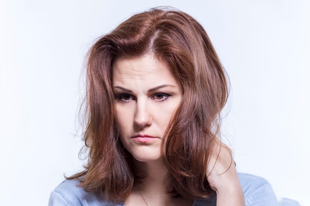 Sad pensive woman in a blue sweater White background Closeup