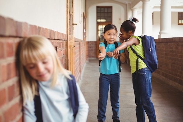 Sad pupil being bullied by classmates at corridor