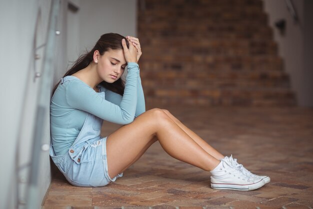 Sad schoolboy sitting in corridor