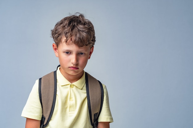 Sad schoolboy with backpack isolated