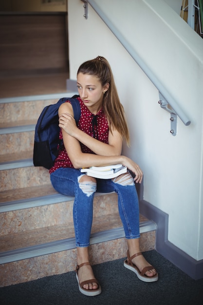 Photo sad schoolgirl sitting alone on staircase