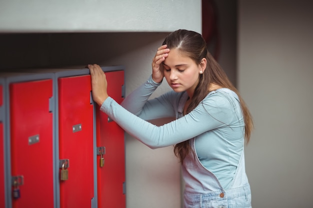 Sad schoolgirl standing in locker room