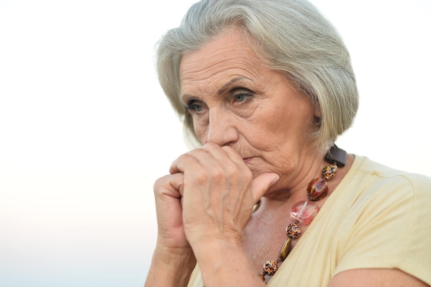 Sad senior beautiful woman in park