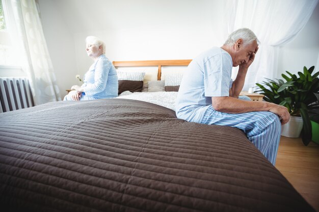 Sad senior couple sitting on bed