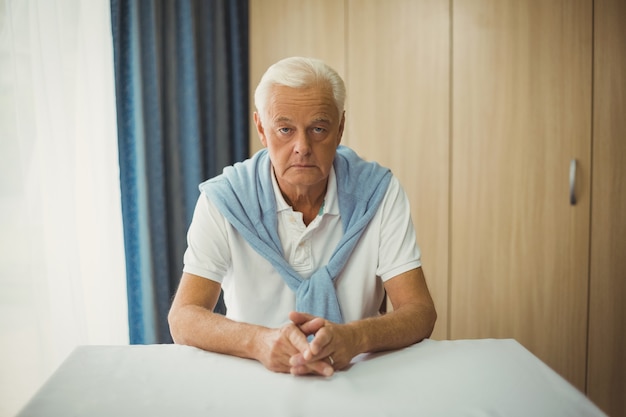 Sad senior man sitting at table