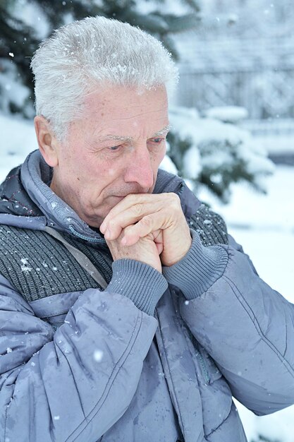 冬に屋外に立っている悲しい年配の男性