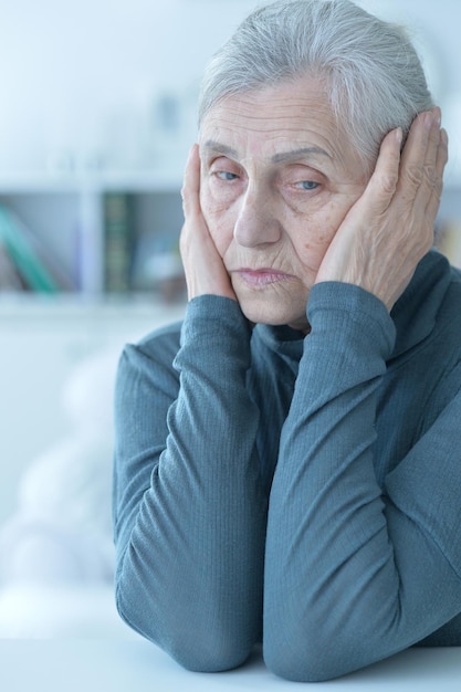 Sad senior woman sitting at table