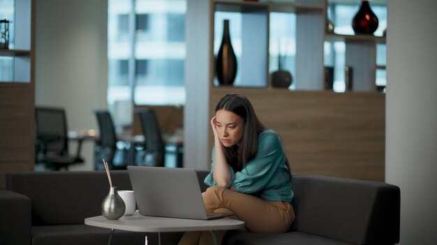 Sad specialist looking solution in office woman watching laptop searching idea