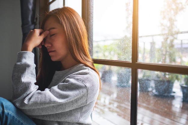 部屋に一人で座っている悲しくてストレスの多い若いアジアの女性