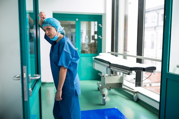 Sad surgeon leaning against the glass door