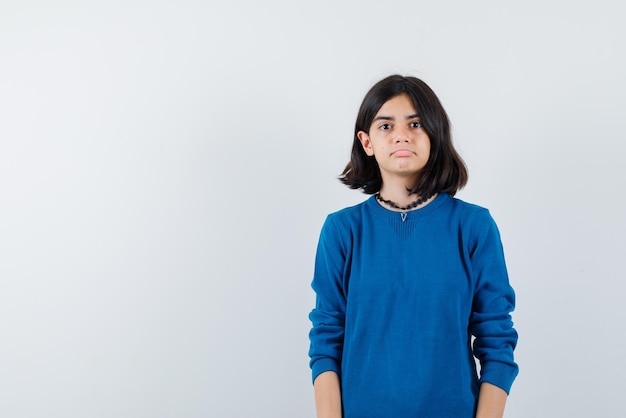 The sad teenage girl is looking at camera on white background