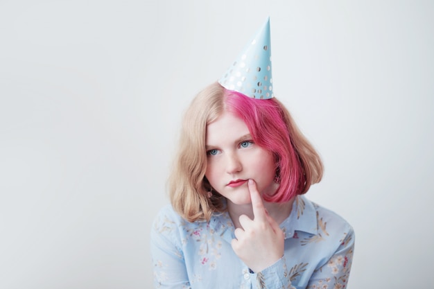 Ragazza triste dell'adolescente in cappello di compleanno