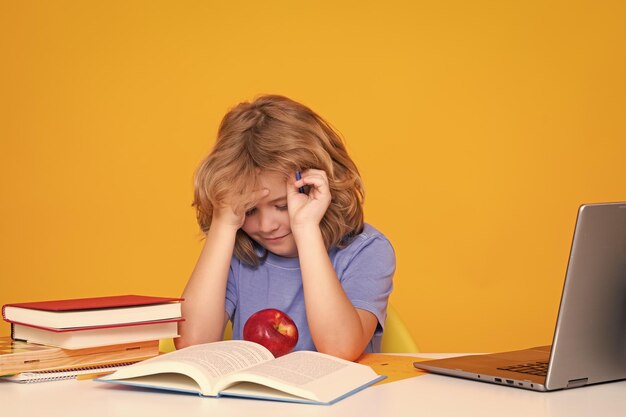 Sad tired and bored pupil Back to school Portrait of cute child school boy School and education kids concept Clever kid with school supplies isolated on yellow studio background