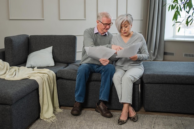 sad tired disappointed middle aged senior couple sit with paper document unhappy older mature man