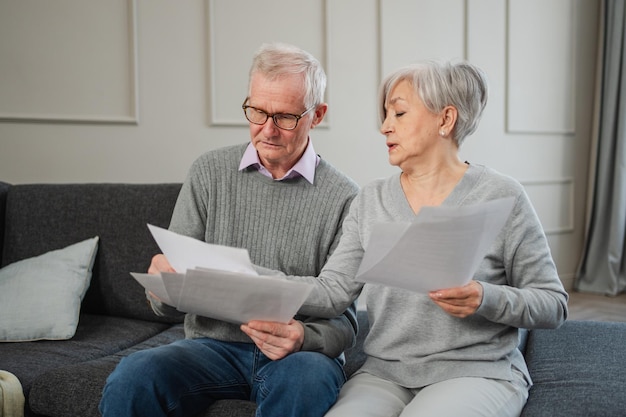 Photo sad tired disappointed middle aged senior couple sit with paper document unhappy older mature man