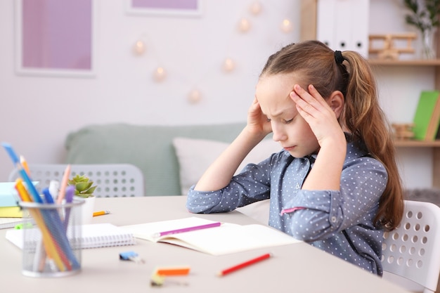 Photo sad tired girl does homework in the interior of the room