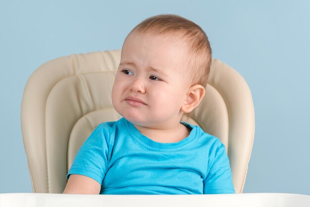 Sad toddler crying sitting on a feeding chair