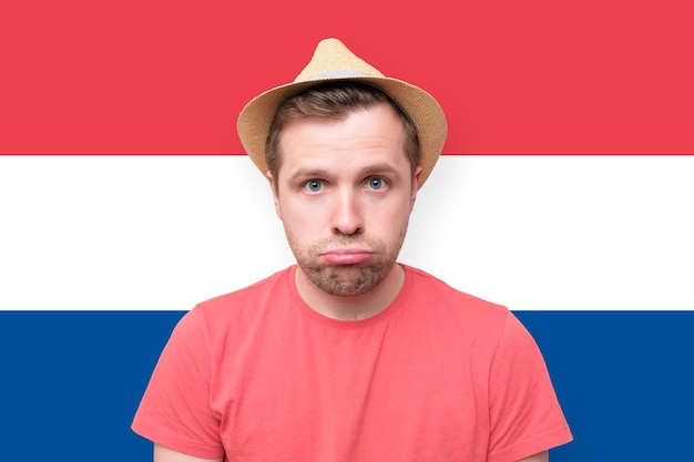 Sad tourist man on dutch flag background