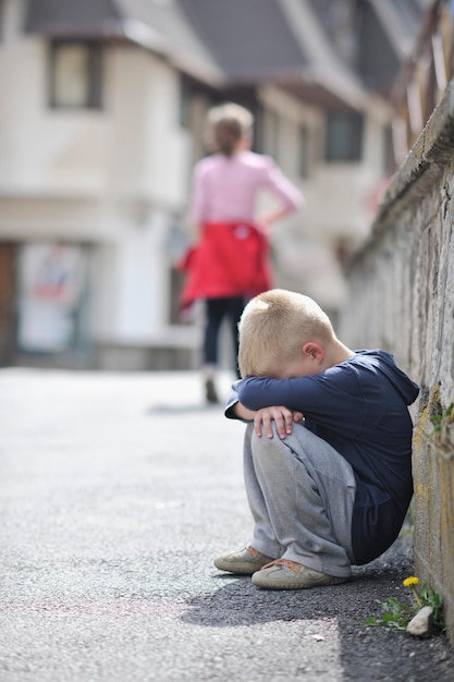 悲しくて不幸な一人の子供が路上で泣き、感情的な問題を抱えている