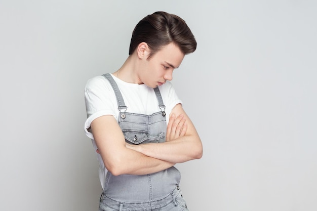 Sad unhappy brunette man standing with folded hands frowns face upset with bad news he received