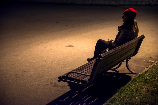 Photo sad unhappy woman sitting on bench in loneliness and looking away. stressed woman in a night time