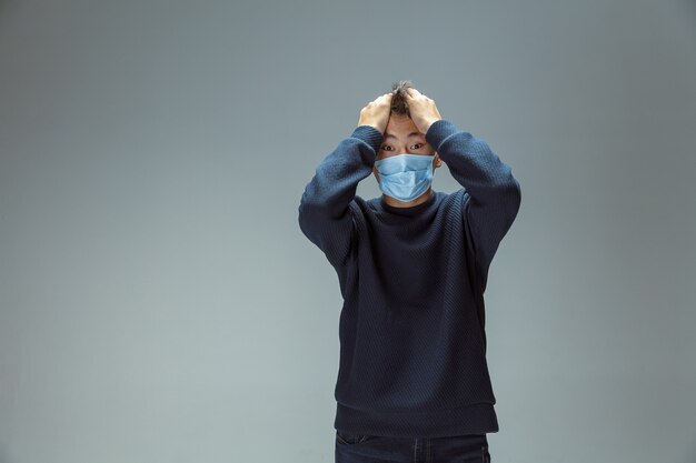 Sad upset Chinese man in blue protective mask posing Prevention against pneumonia