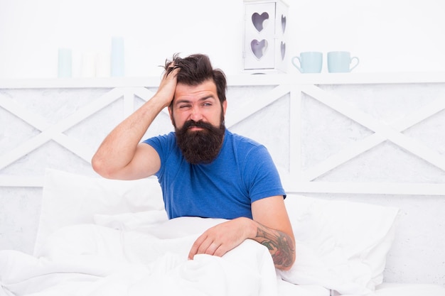 Foto uomo triste e sconvolto che si sveglia al mattino con mal di testa, dolore e salute