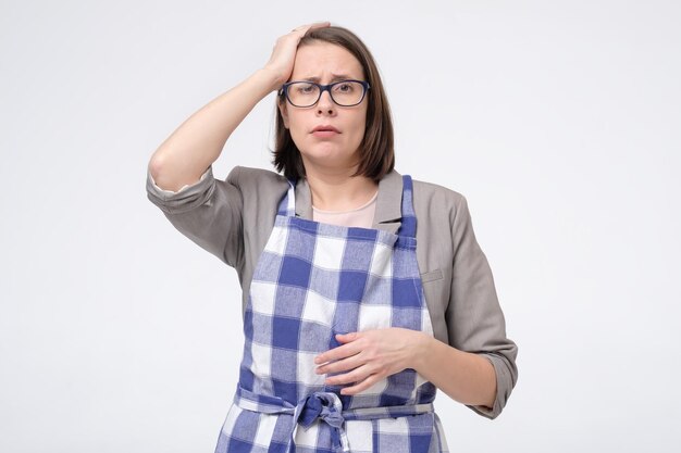 Sad upset tired businees woman in apron touch her hand to head has no power