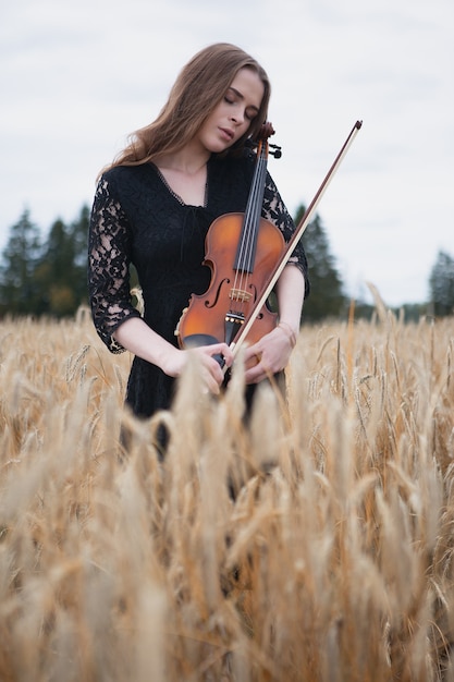 The sad violinist gently presses her violin to her