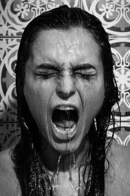Грустная и мокрая женщина с размазанным макияжем на лице под душем