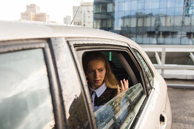 Sad woman at car window during rainy day