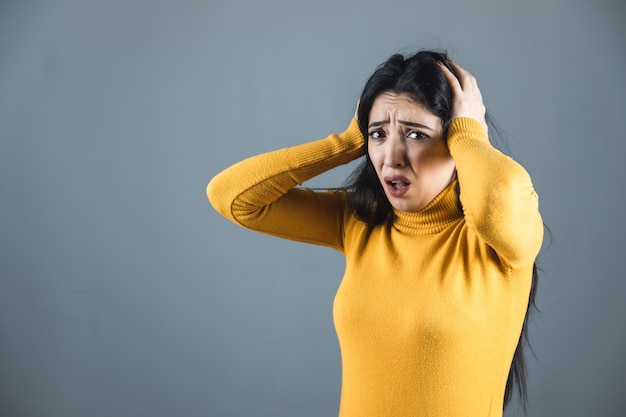 Sad woman hand in head on grey background