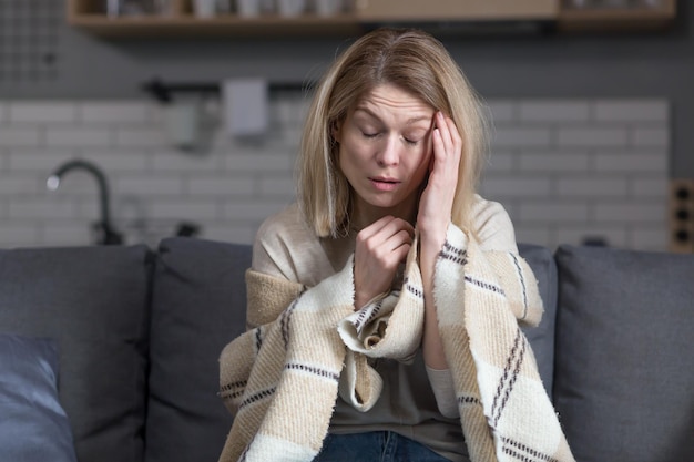 Sad woman at home sitting on sofa alone in depression crying