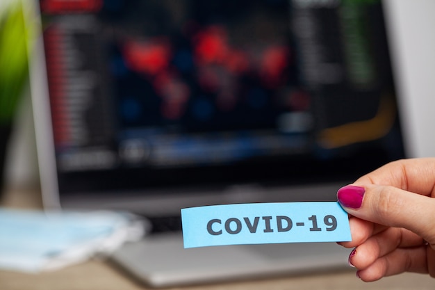 La donna triste sta guardando i grafici di borsa che cadono durante un'epidemia covid-19.