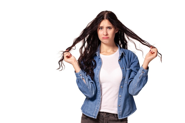 Sad woman is pulling her hair on white background