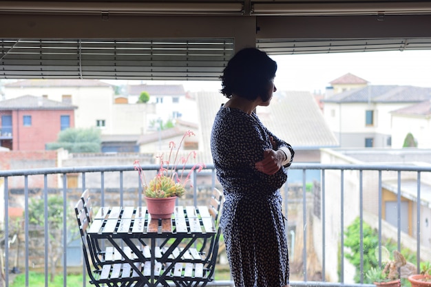 A sad woman looking out the window at home