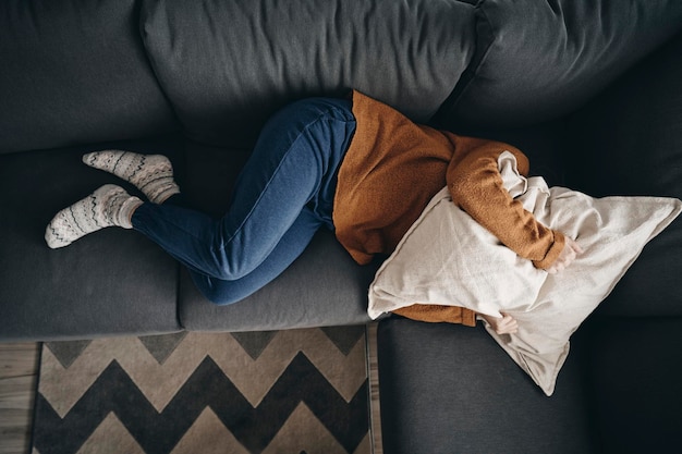 sad woman lying on sofa at home