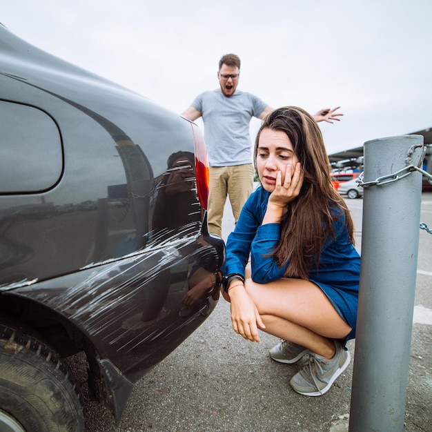 sad woman near scratched car man shouting on woman car acciden