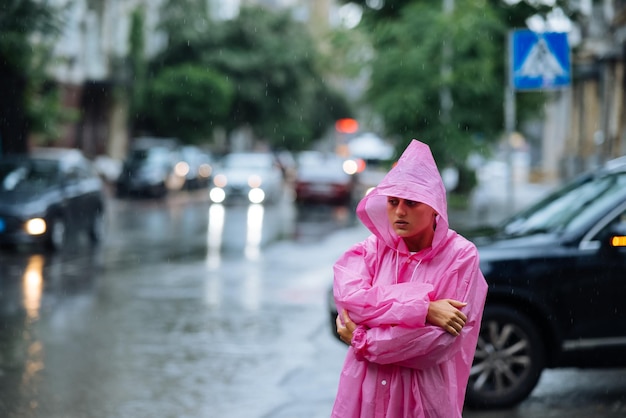 雨の中の路上でレインコートを着た悲しい女性