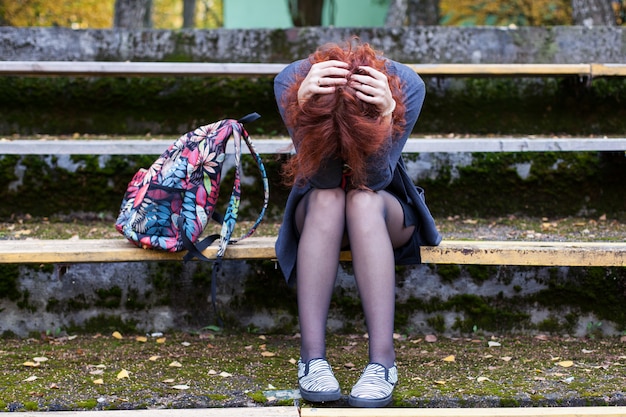 Donna triste che si siede sulla panchina nel parco