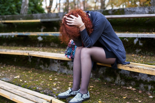 Foto donna triste che si siede sulla panchina nel parco