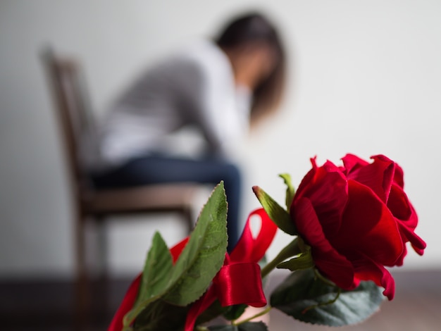 悲しい女性は、座って、泣いて、赤いバラに焦点を当てた。