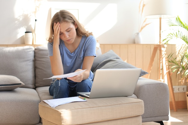 Sad woman sitting on a sofa in the living room.