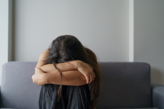 Photo sad woman thinking about problems sitting on a sofa upset girl feeling lonely and sad from bad relationship or depressed woman disorder mental health