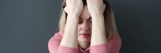 Sad woman with closed eyes holding her head with her hands loneliness concept