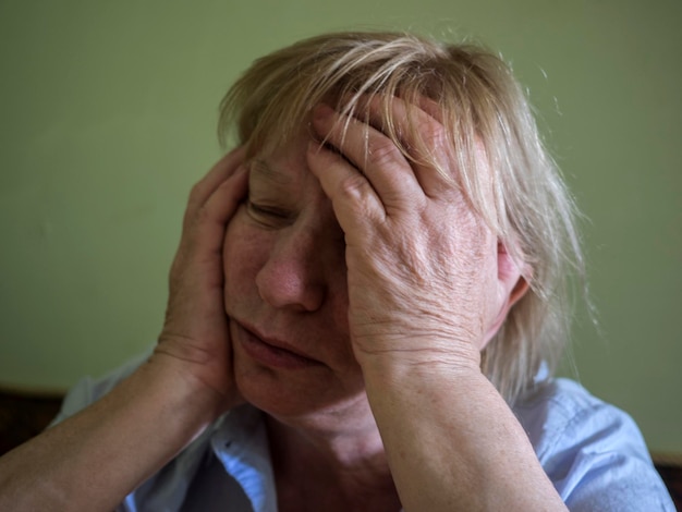 Foto donna triste con la testa tra le mani contro il muro verde a casa