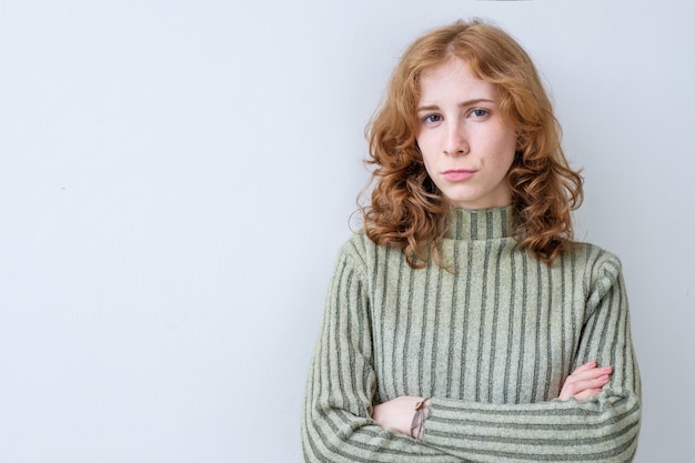 Donna triste con lunghi capelli rossi con le mani incrociate che esprimono la sua insoddisfazione