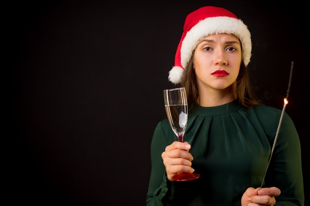 Donna triste con cappello rosso di capodanno e champagne