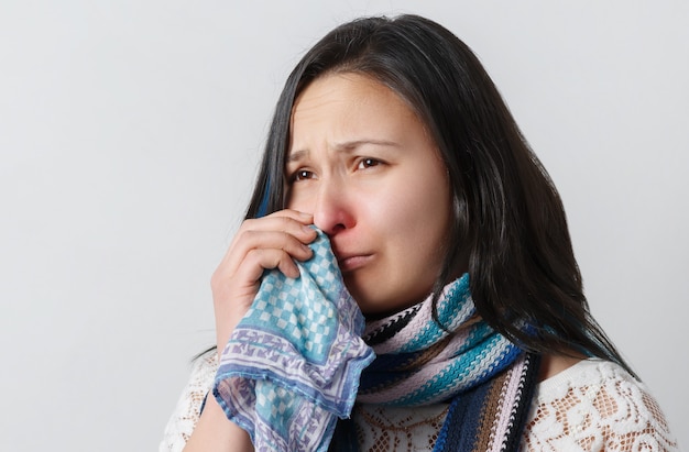 sad woman with runny nose uses handkerchief